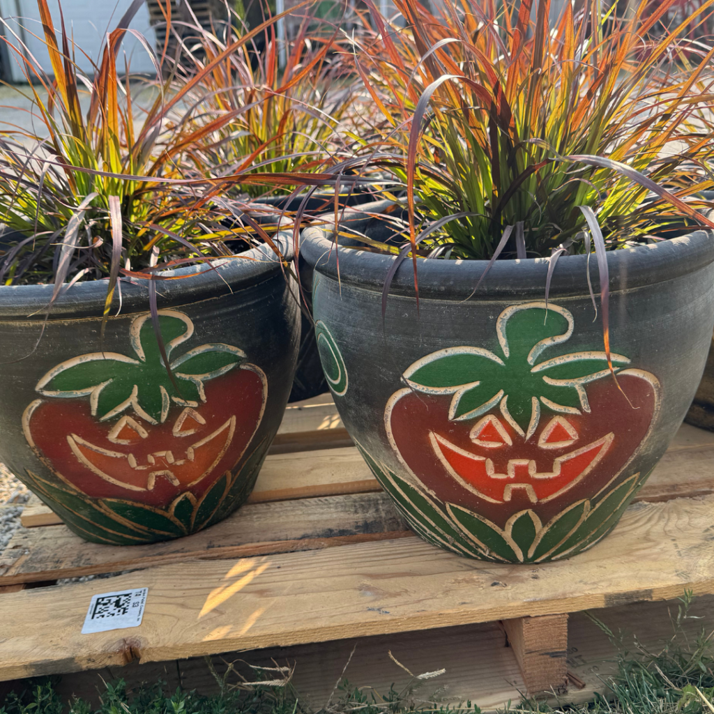 Ceramic pot with a Halloween face on it with grass sticking out of it.